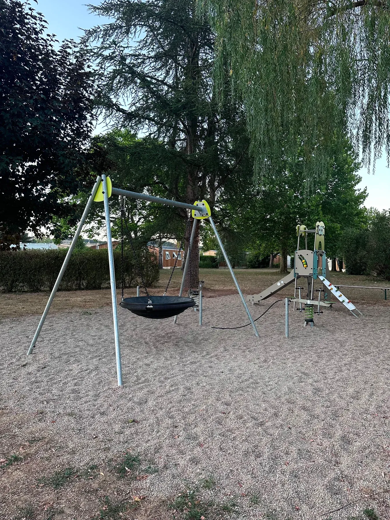 Parc de Charlieu — La balançoire nid et le toboggan, au pied des grands arbres
