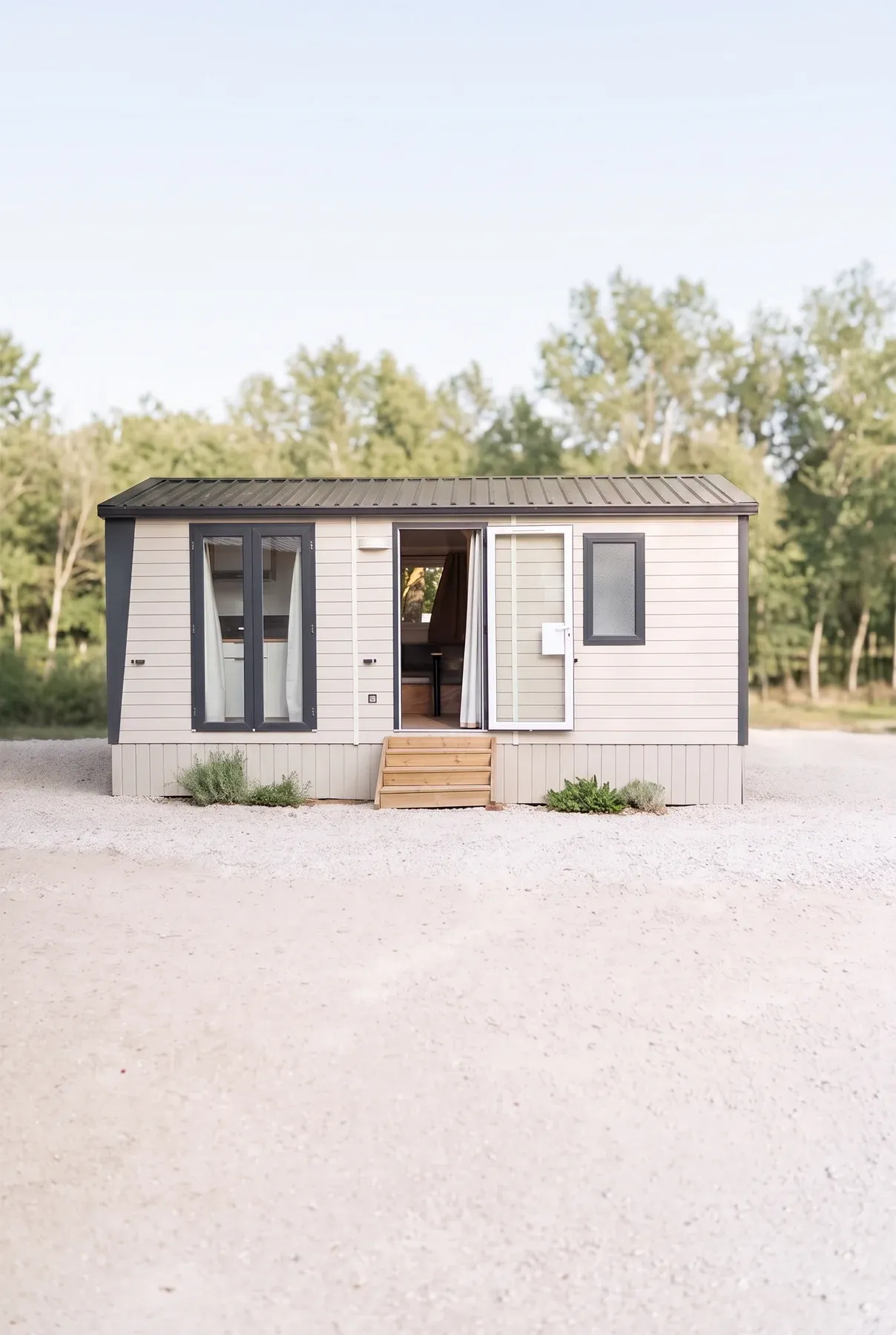 Mobil-home NEST 24.2 — Le NEST 24.2 sur sa parcelle, porte ouverte sur le séjour