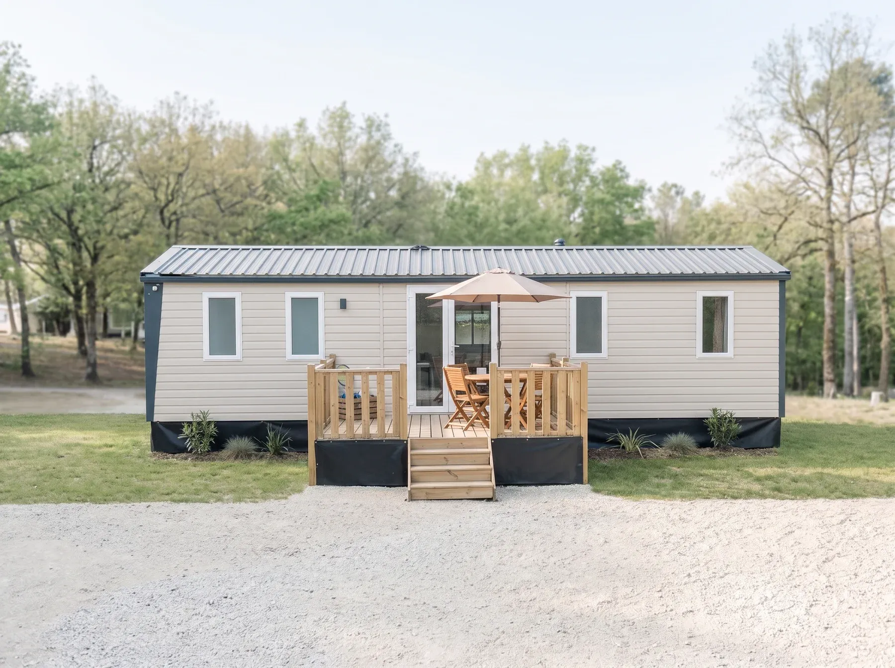 Mobil-home NEST 40.3 SAND — Le NEST 40.3 SAND sur sa parcelle, façade et terrasse bois avec parasol