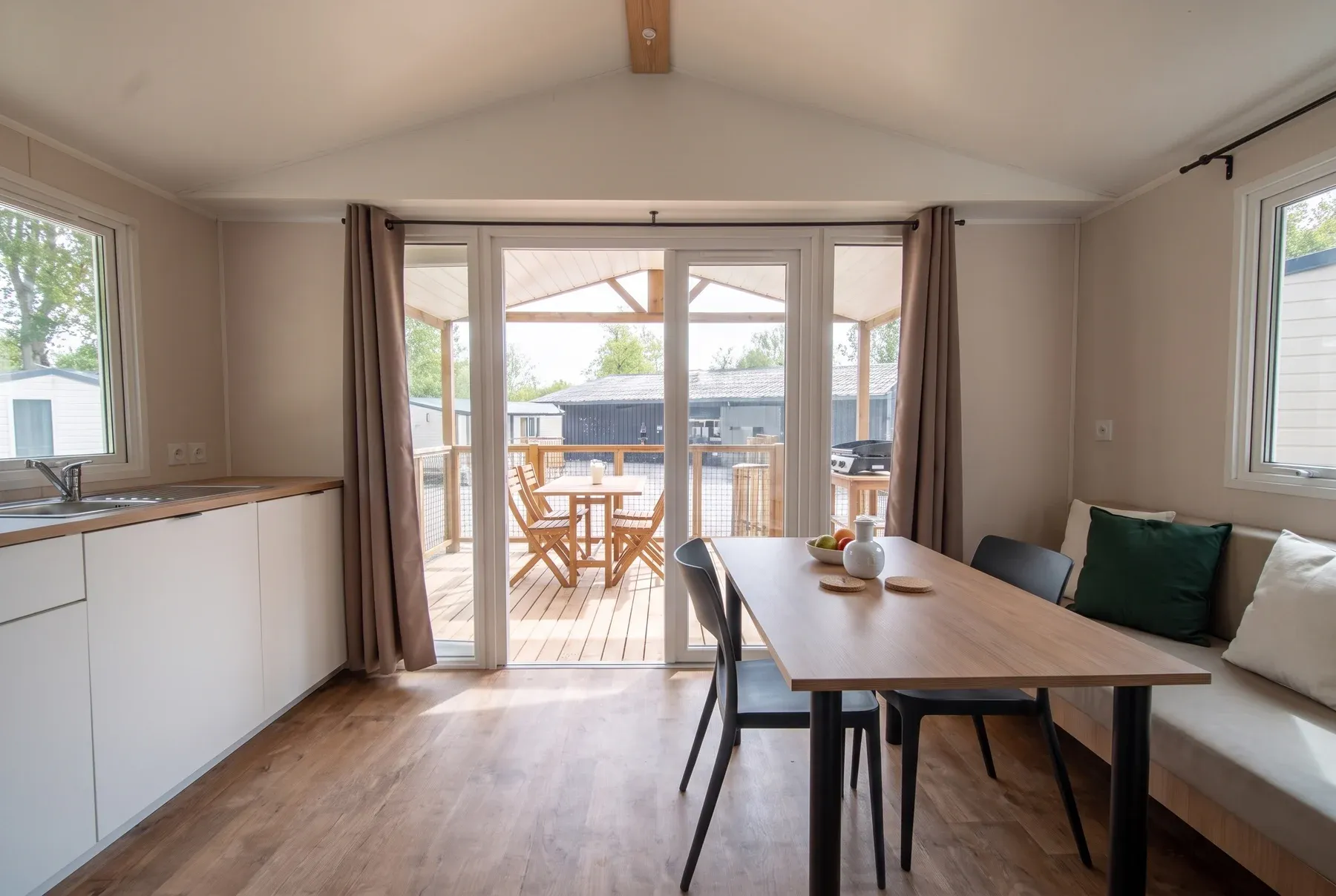 NEST PANO 38.2 — Le séjour et son coin repas, baie vitrée ouverte sur la terrasse