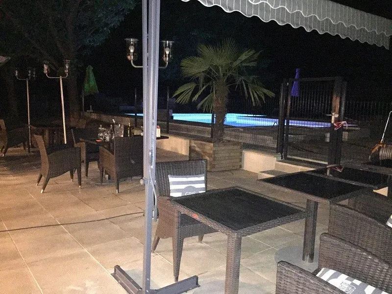 Parc de Coullons Grand Parc — La terrasse et la piscine éclairée, à la tombée du jour